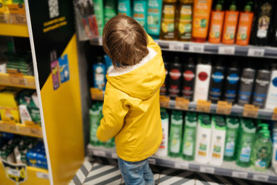 Child in the market chooses a product, rear view