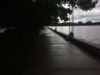 Walkway amidst trees against sky