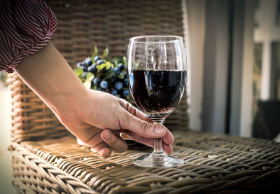 Midsection of woman holding wineglass on table