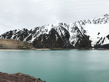 Scenic view of lake by snowcapped mountain against sky