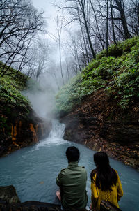 Rear view of friends against waterfall in forest