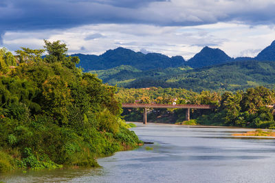 Scenic view of river by mountains against sky