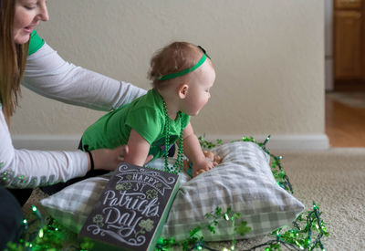 Mother holding baby girl by decoration sitting on floor