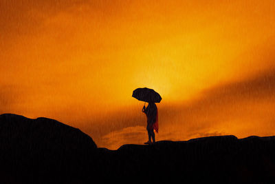 Silhouette woman holding umbrella against sky during sunset
