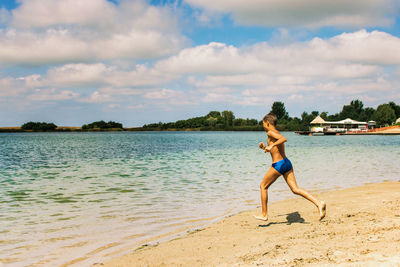 Boy running at beach against sky