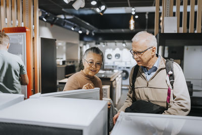 Senior couple examining refrigerator while shopping in appliances store
