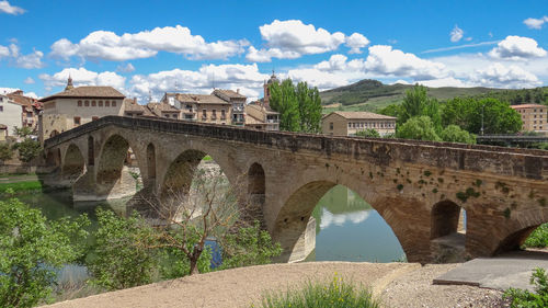 Arch bridge over river against sky