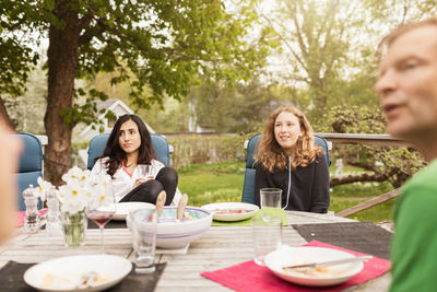 Teenage girls sitting with father at table in yard