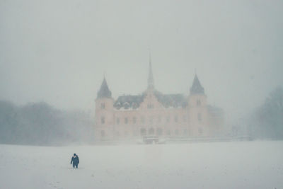 People on snow covered building against sky