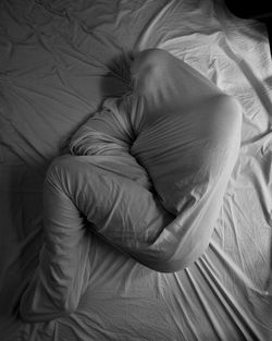 High angle view of man wrapped in blanket lying on bed