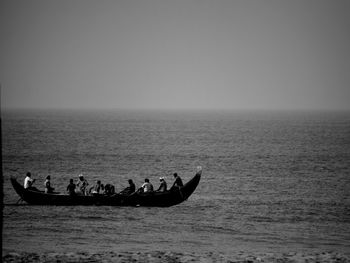 People on boat in sea against sky