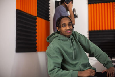 Boy with green hoodie sitting in recording studio