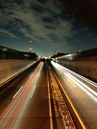 Light trails on road in city against sky