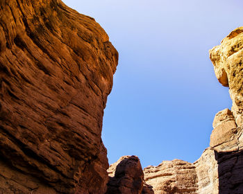 Low angle view of rocky mountain against clear sky