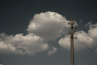 Low angle view of silhouette electricity pylon against sky