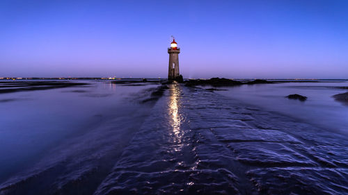 Lighthouse by sea against sky