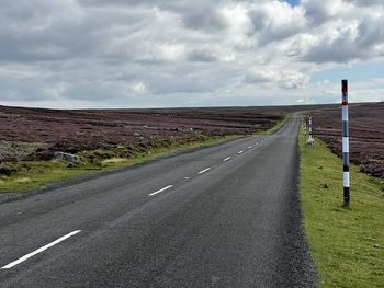 Road amidst field against sky