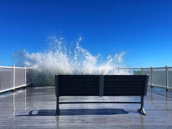 View of empty bench against clear blue sky