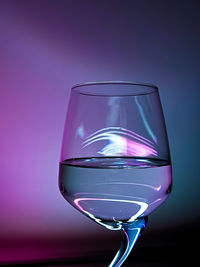 Close-up of glass of water against blue and purple background