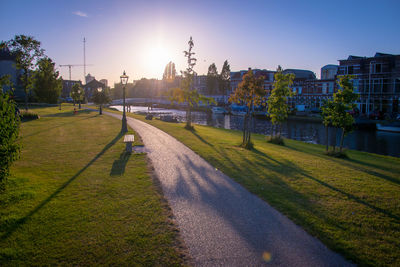 Park by buildings against sky during sunset