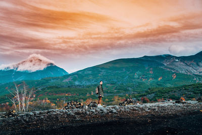 Rear view of woman standing on mountain against sky