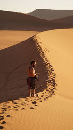 Full length of boy on sand at beach against sky