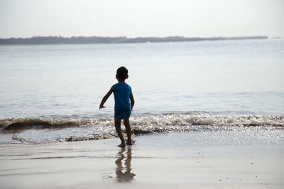 Full length of boy on beach against sky