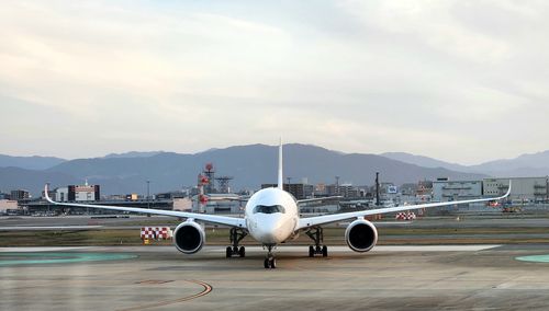 Airplane on airport runway against sky