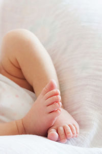 Low section of baby lying on bed