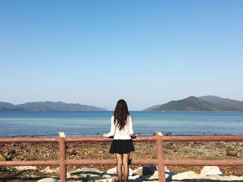 Rear view of woman looking at sea against clear sky