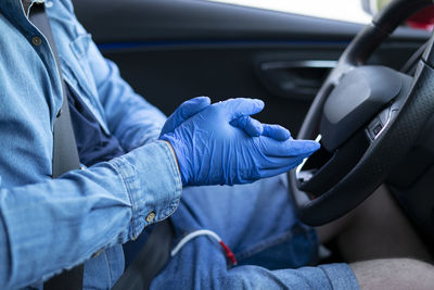 Man in the car disinfecting his hands. driving and covid-19 concept.