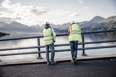 Rear view of construction workers standing by railing