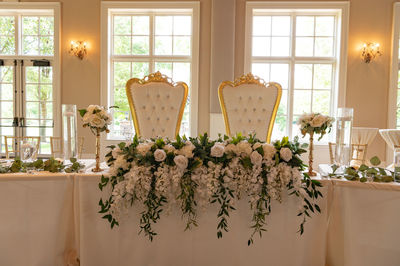 Chairs for bride and groom and table decorated with flowers