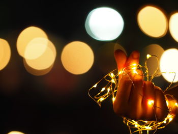 Close-up of hand holding illuminated lighting equipment