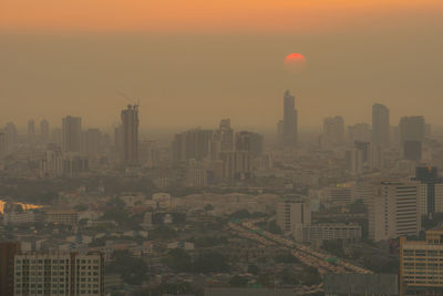 Aerial view of buildings in city against sky during sunset