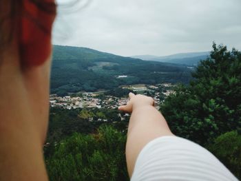 Low section of people relaxing on mountain against sky