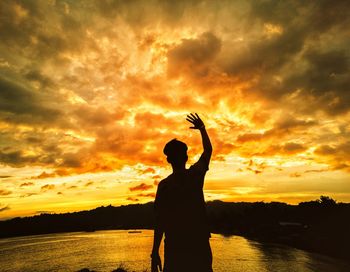 Silhouette man standing by sea against sky during sunset