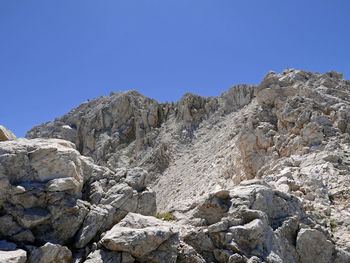 Low angle view of rocks against clear blue sky