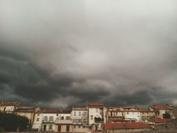 Buildings in city against storm clouds