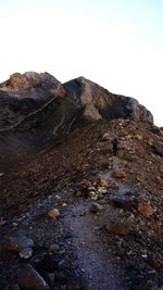 Man with lizard on rock against sky