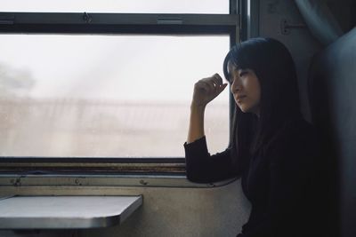 Young woman standing against window