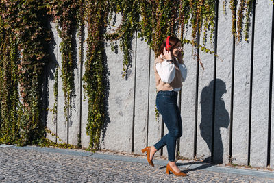 Side view of beautiful redhead woman smiling while listening music with red headphones. copy space