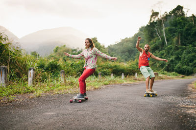 Friends skateboarding on road against sky