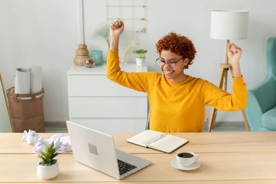 Portrait of young woman using laptop while sitting on table