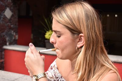 Profile view of young woman igniting cigarette outdoors