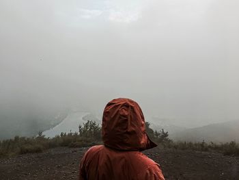 Rear view of man standing on mountain against sky