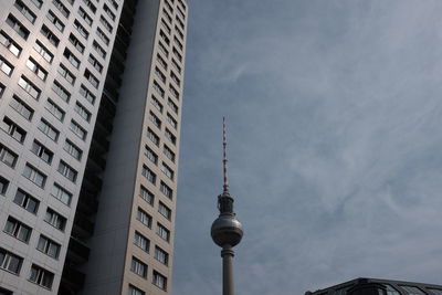 Low angle view of fernsehturm tower by building against sky