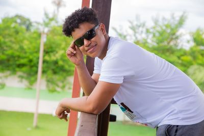 Side view of young man holding sunglasses