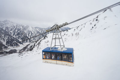 Overhead cable car on snowcapped mountain against sky