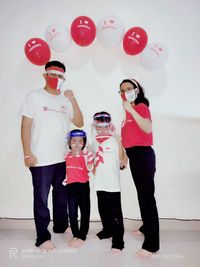 Rear view of people with balloons standing against wall